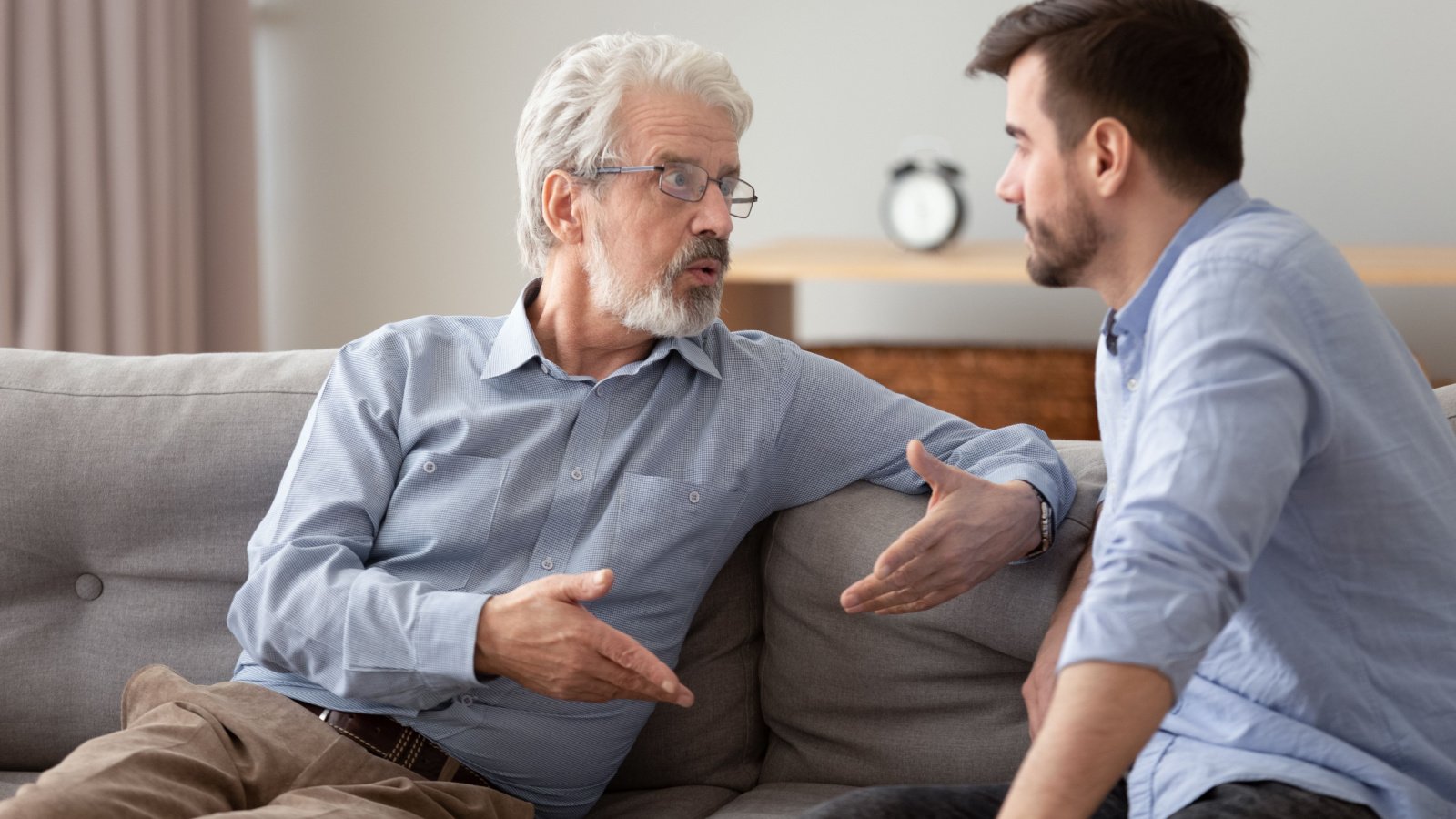 elderly father and grown up adult son sitting on sofa talking having important conversation fight fizkes shutterstock