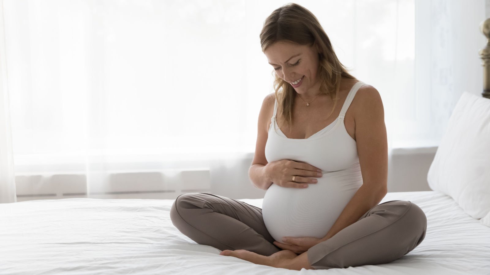 expectant pregnant woman sitting on bed fizkes shutterstock