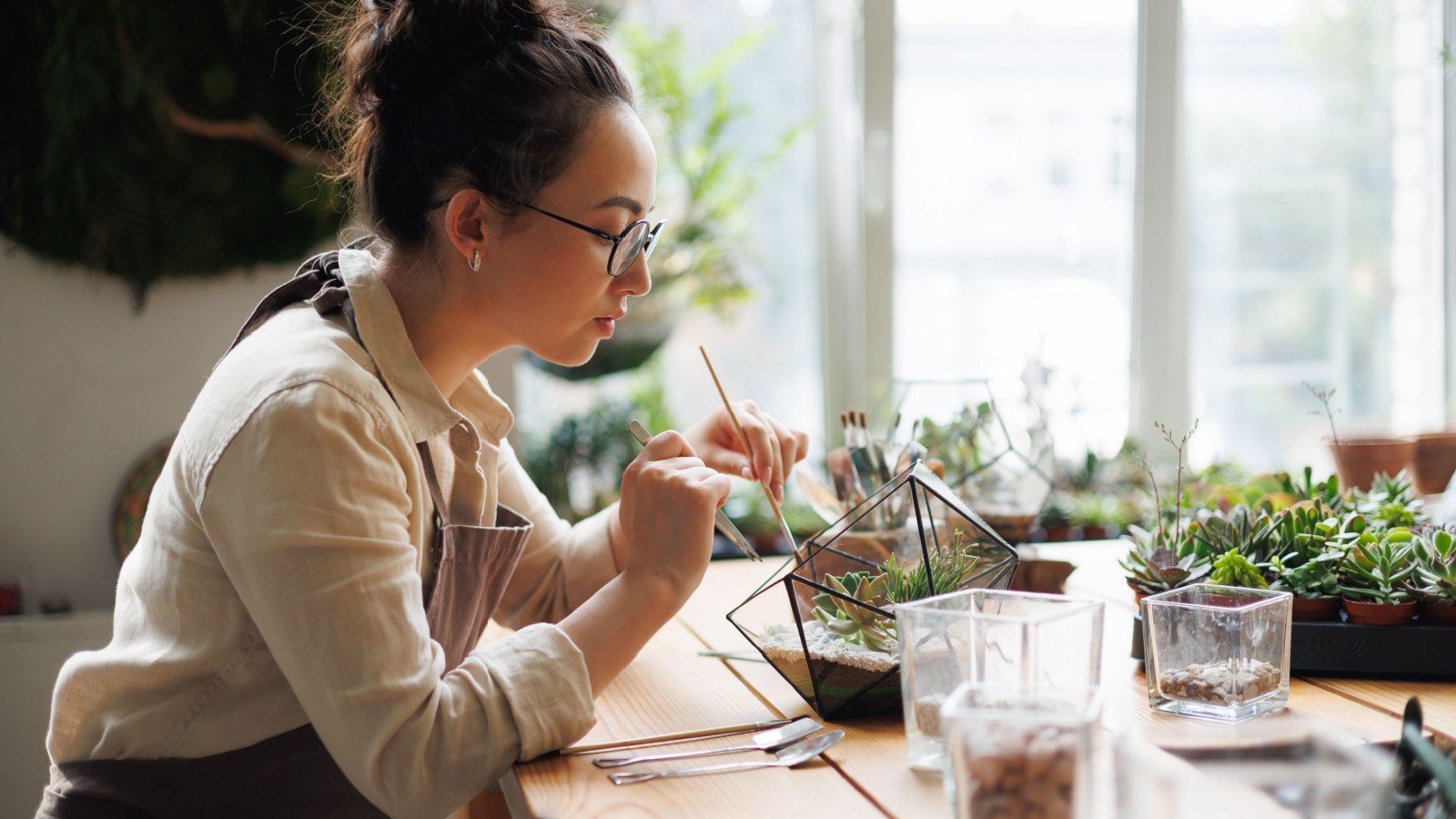 florist with gardening tools creating small garden in terrarium near succulents Dmytro Hai Shutterstock