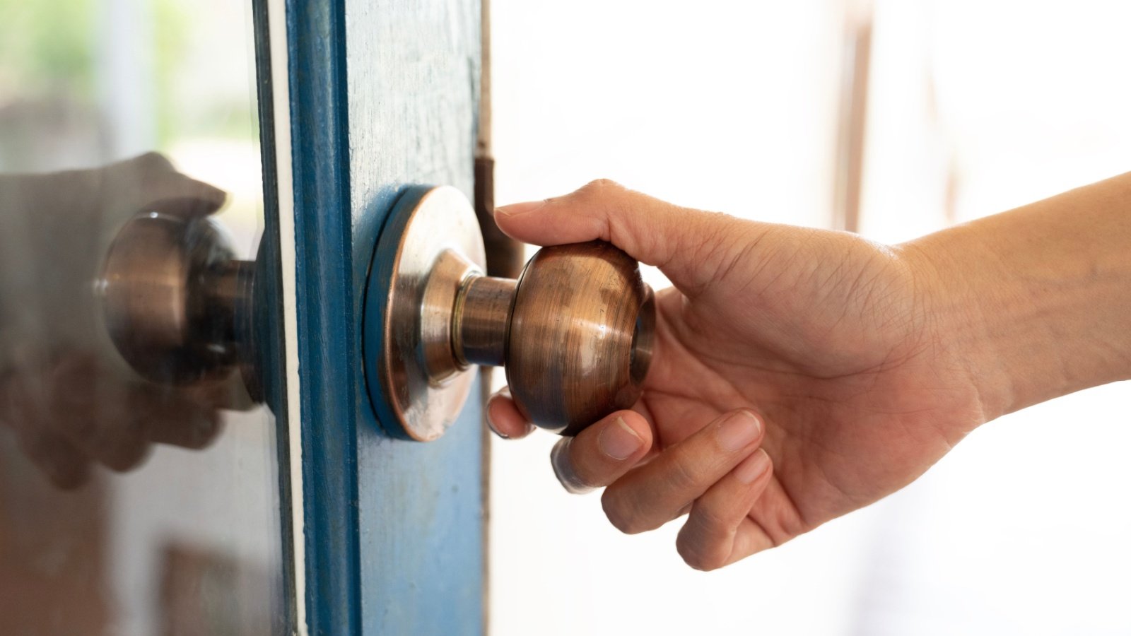 hand hold handle of door doorknob front door home house welcome Chutima Chaochaiya Shutterstock