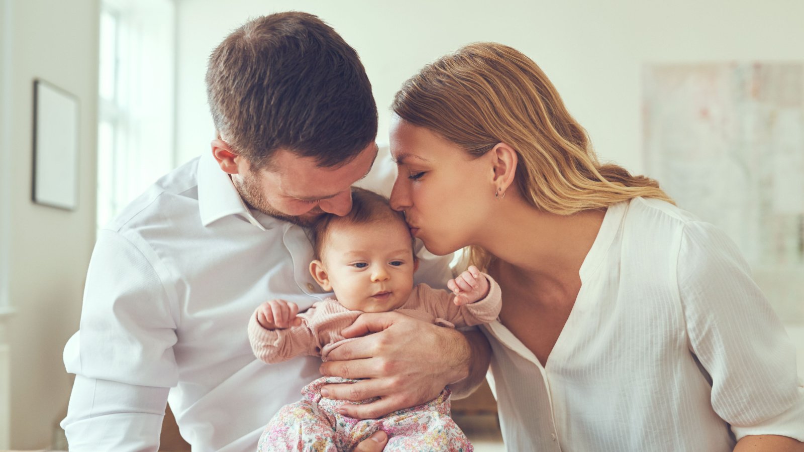 happy couple sitting at a table kissing their newborn baby ground picture shutterstock