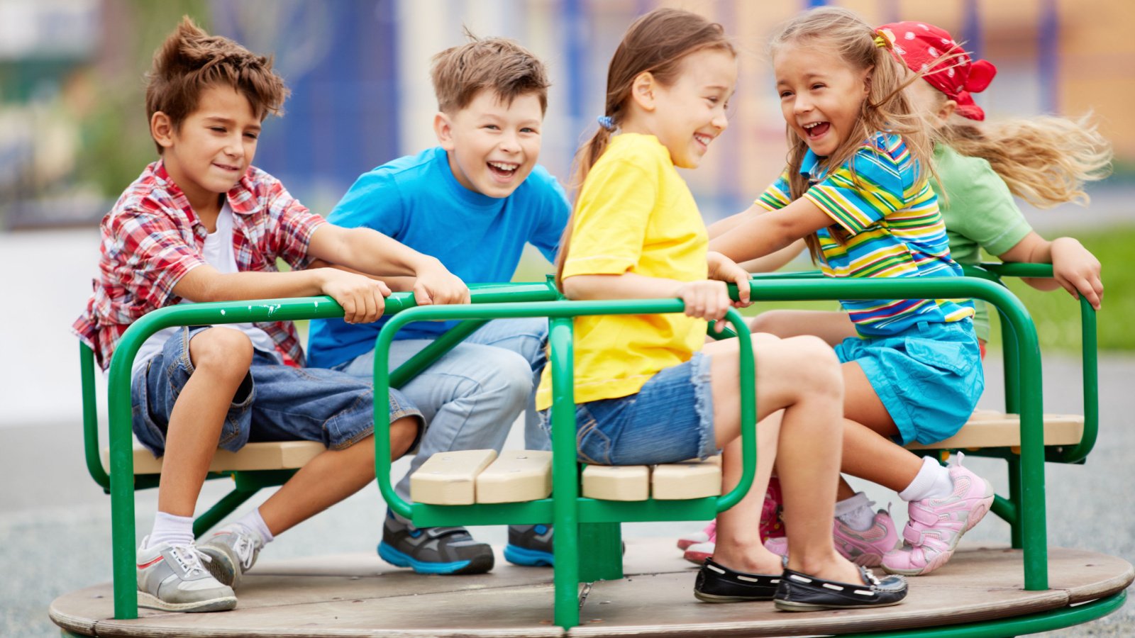 kids playing on carousel playground Pressmaster Shutterstock