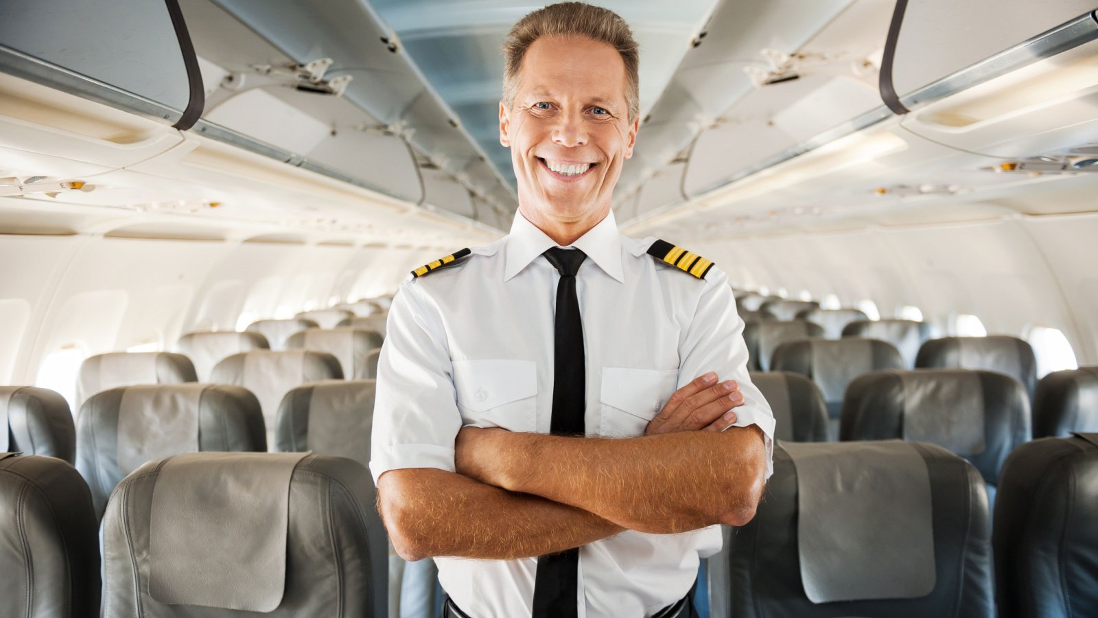 male pilot in uniform keeping arms crossed airplane flight gstock studio shutterstock