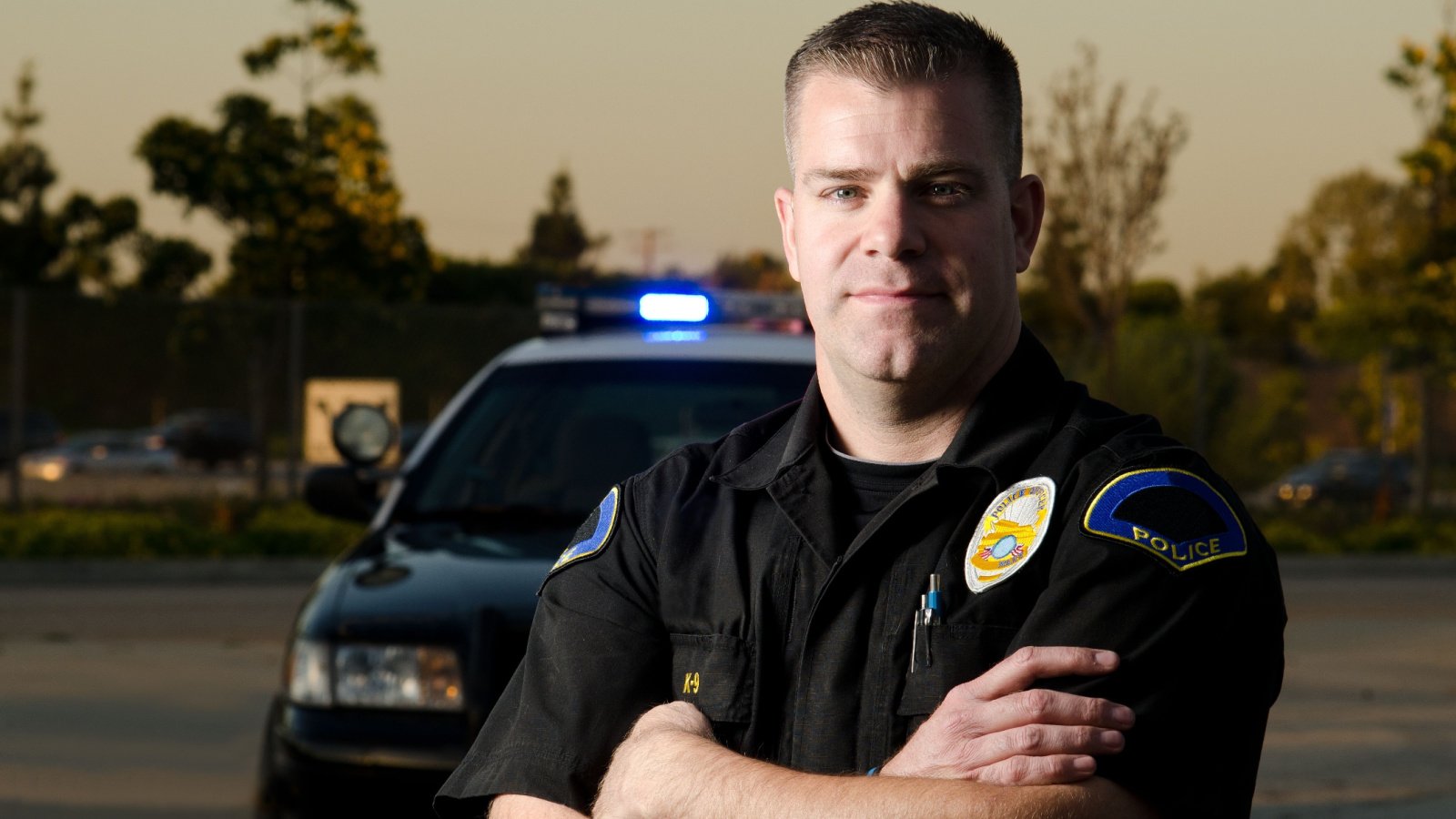 police officer standing in front of his patrol arms cross jobs emergency john roman images shutterstock