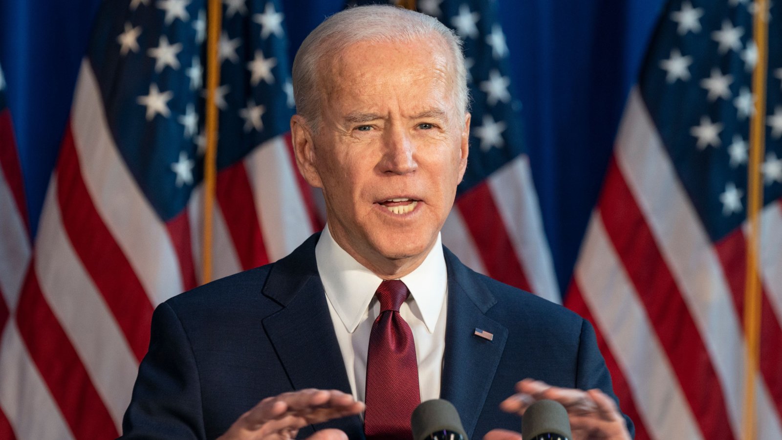 president joe biden speech with flag in background lev radin shutterstock