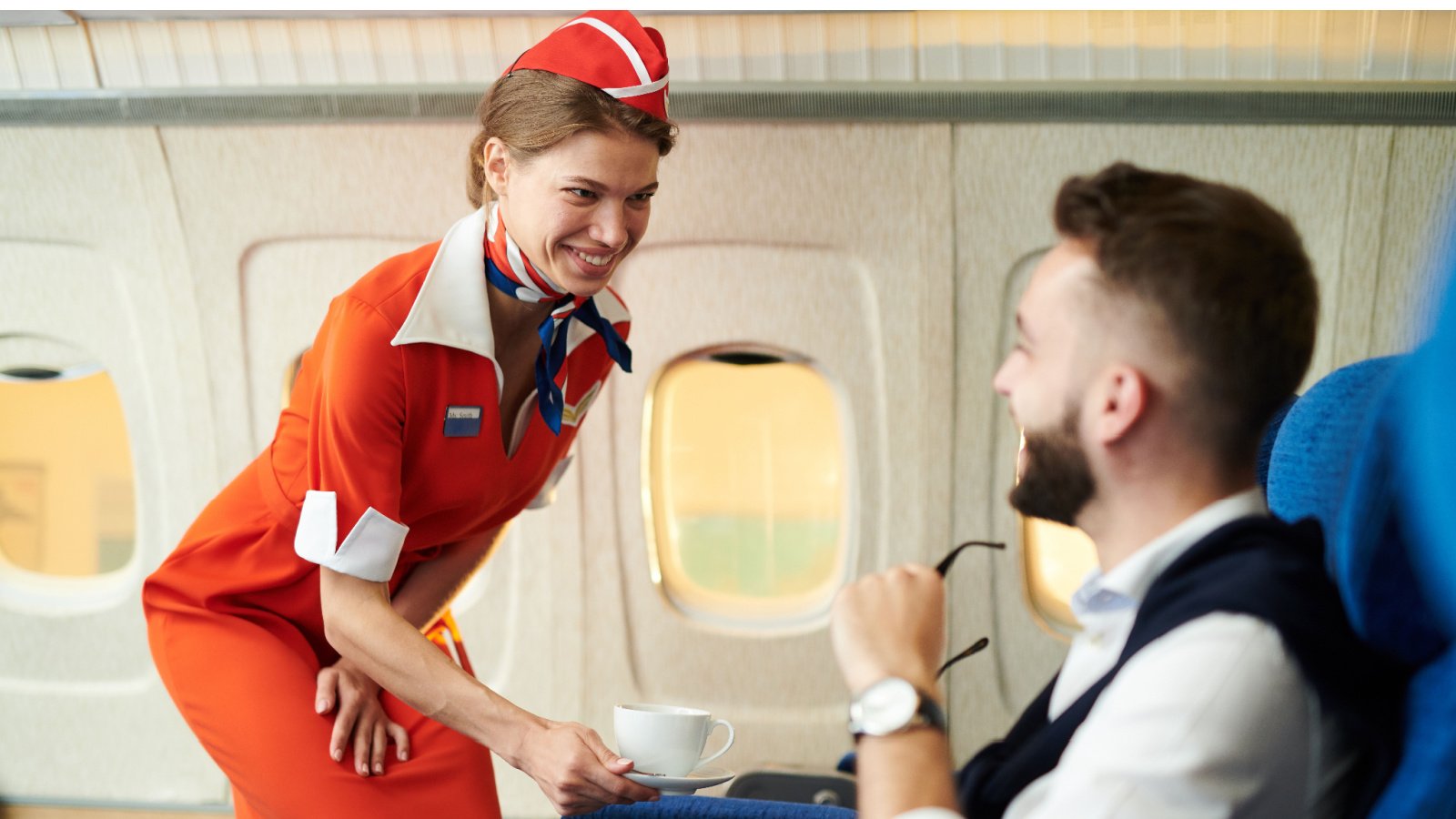 smiling flight attendant serving coffee to passenger in airplane on a flight seventy four shutterstock