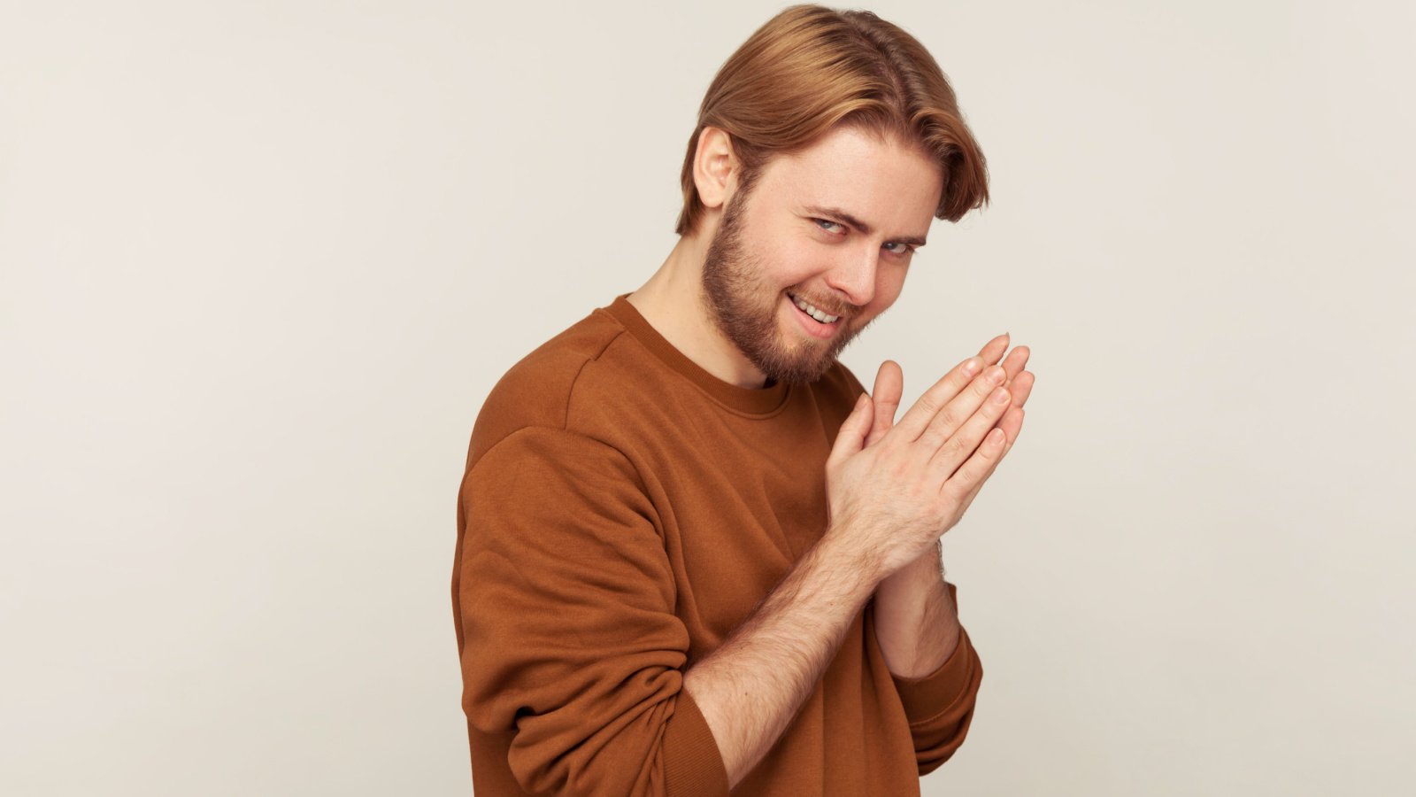 sneaky sly scheming male with beard wearing sweatshirt rubbing palm cunning evil plan revenge khosro shutterstock