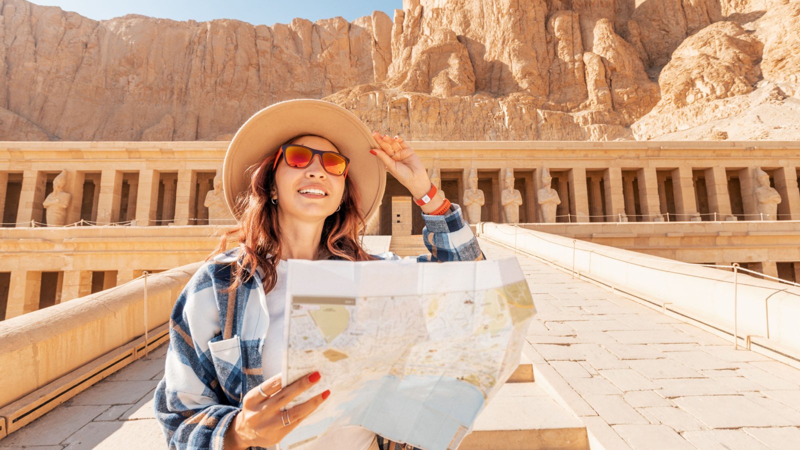 tourist and traveler with a map is exploring the sights of the ancient city of Thebes or modern Luxor standing near the temple of Pharaoh's queen Hatshepsut Egypt frantic00 shutterstock