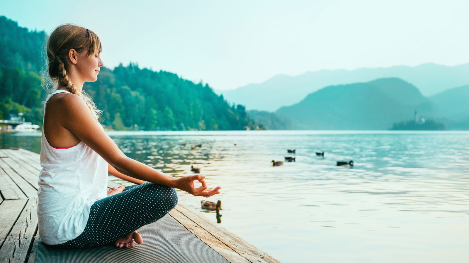 woman in lotus position, meditate by the lake, sunset, water Microgen Shutterstock