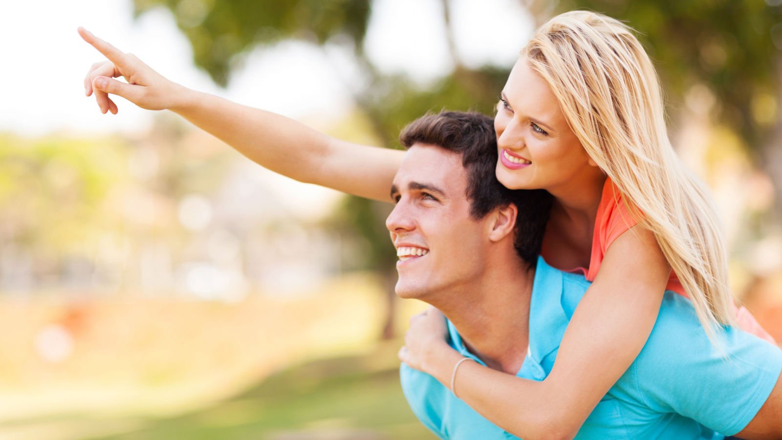 young couple piggyback and pointing outdoors pointing michaeljung shutterstock