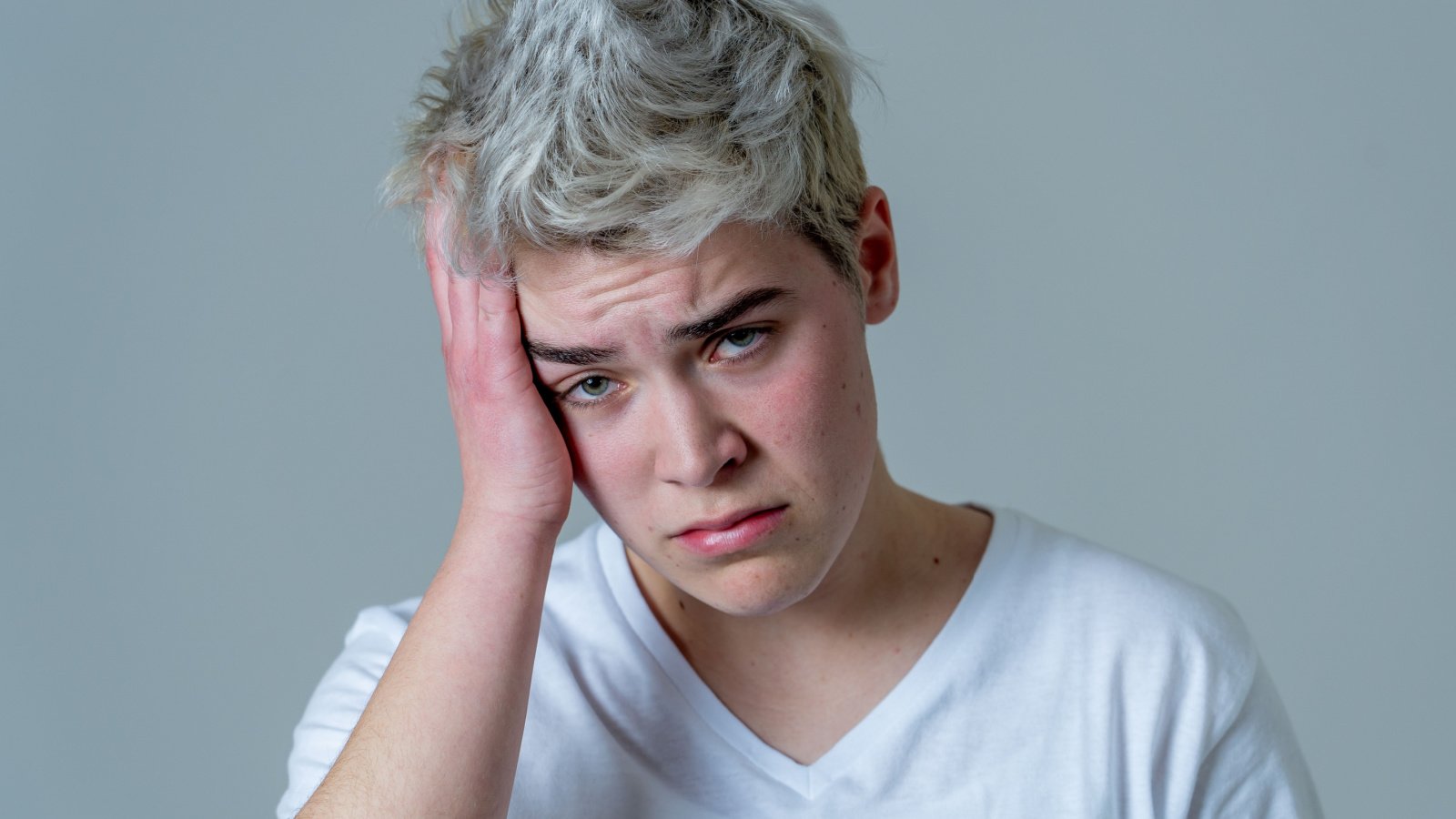 young transgender teen looking worried and thoughtful lbgtq suffering from migraines gender non binary sb arts media shutterstock